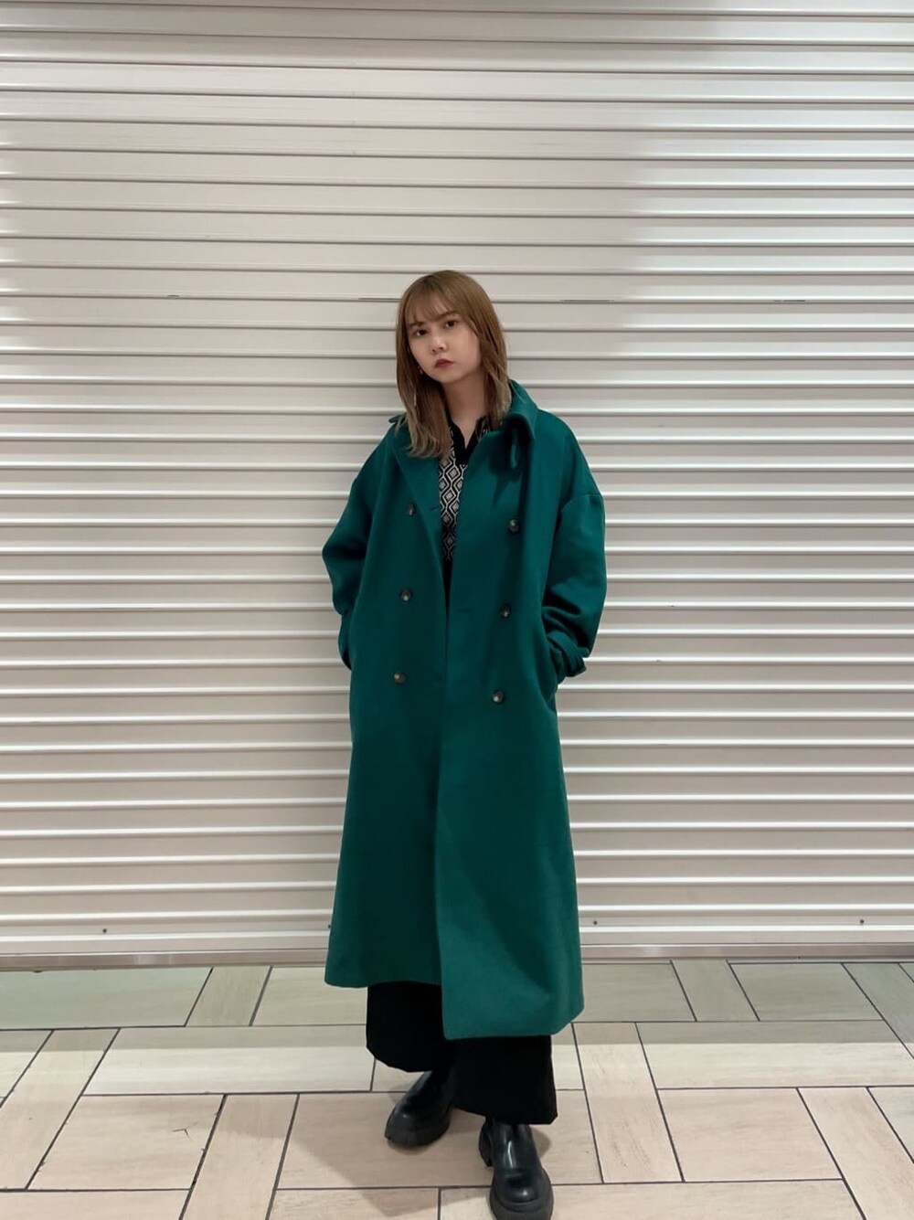 ブラック系のスラックス、ブラック系のニット/セーター、グリーン系のステンカラーコートを着用したレディースの夏コーディネートの2枚目の写真