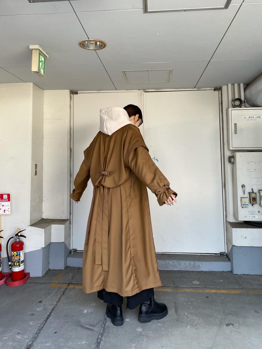 ブラウン系のトレンチコート、ブラック系のスラックス、ブラック系のブーツを着用したレディースの秋コーディネートの3枚目の写真