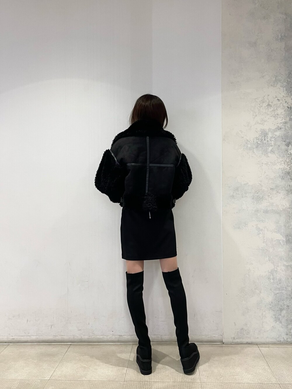 ブラック系のムートンコート、イエロー系のニット/セーター、ブラック系のスカートを着用したレディースの秋コーディネートの3枚目の写真