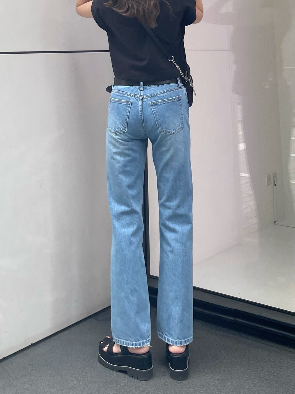 ブラック系のTシャツ/カットソー、ブルー系のデニムパンツ、ブラック系のサンダルを着用したレディースの春コーディネートの5枚目の写真