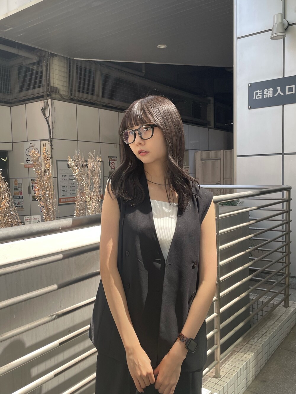 ブラック系のテーラードジャケット、ホワイト系のタンクトップ、ブラック系のスラックスを着用したレディースの春コーディネートの4枚目の写真