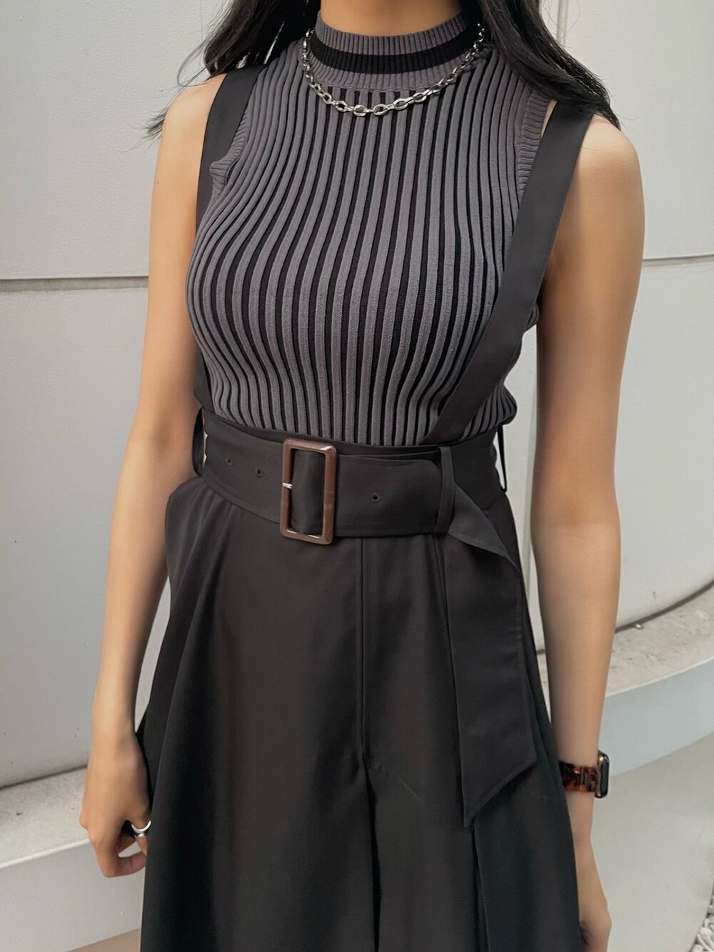 ブラック系のニット/セーター、ブラック系のジャンパースカート、ブラック系のサンダルを着用したレディースの春コーディネートの5枚目の写真