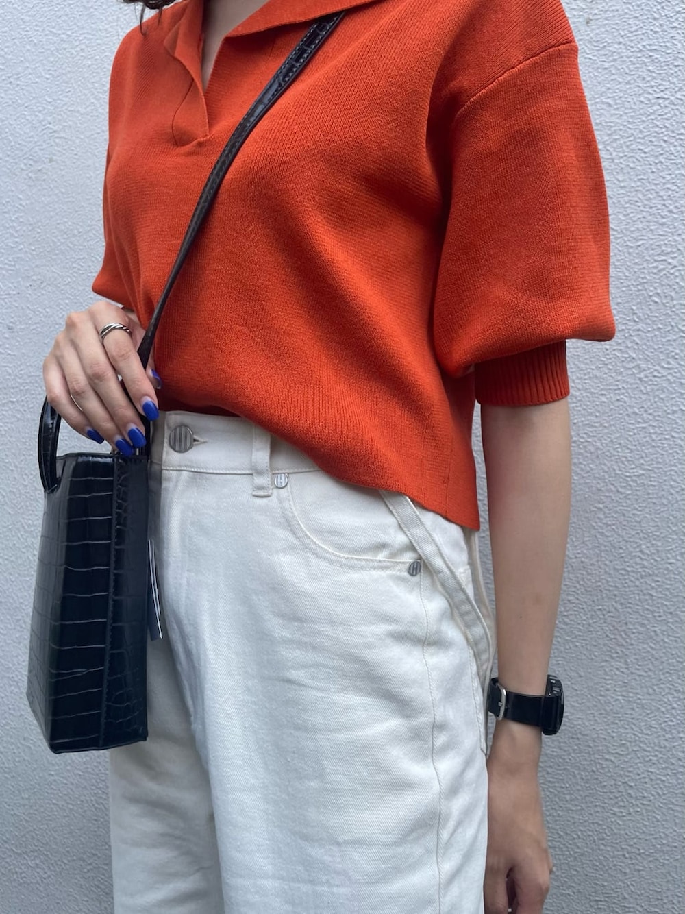 オレンジ系のポロシャツ、ホワイト系のデニムパンツ、ブラック系のサンダルを着用したレディースの夏コーディネートの6枚目の写真