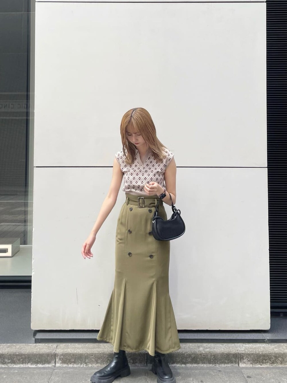 ベージュ系のスカート、ブラック系のハンドバッグ、ベージュ系のニット/セーターを着用したレディースの夏コーディネートの2枚目の写真