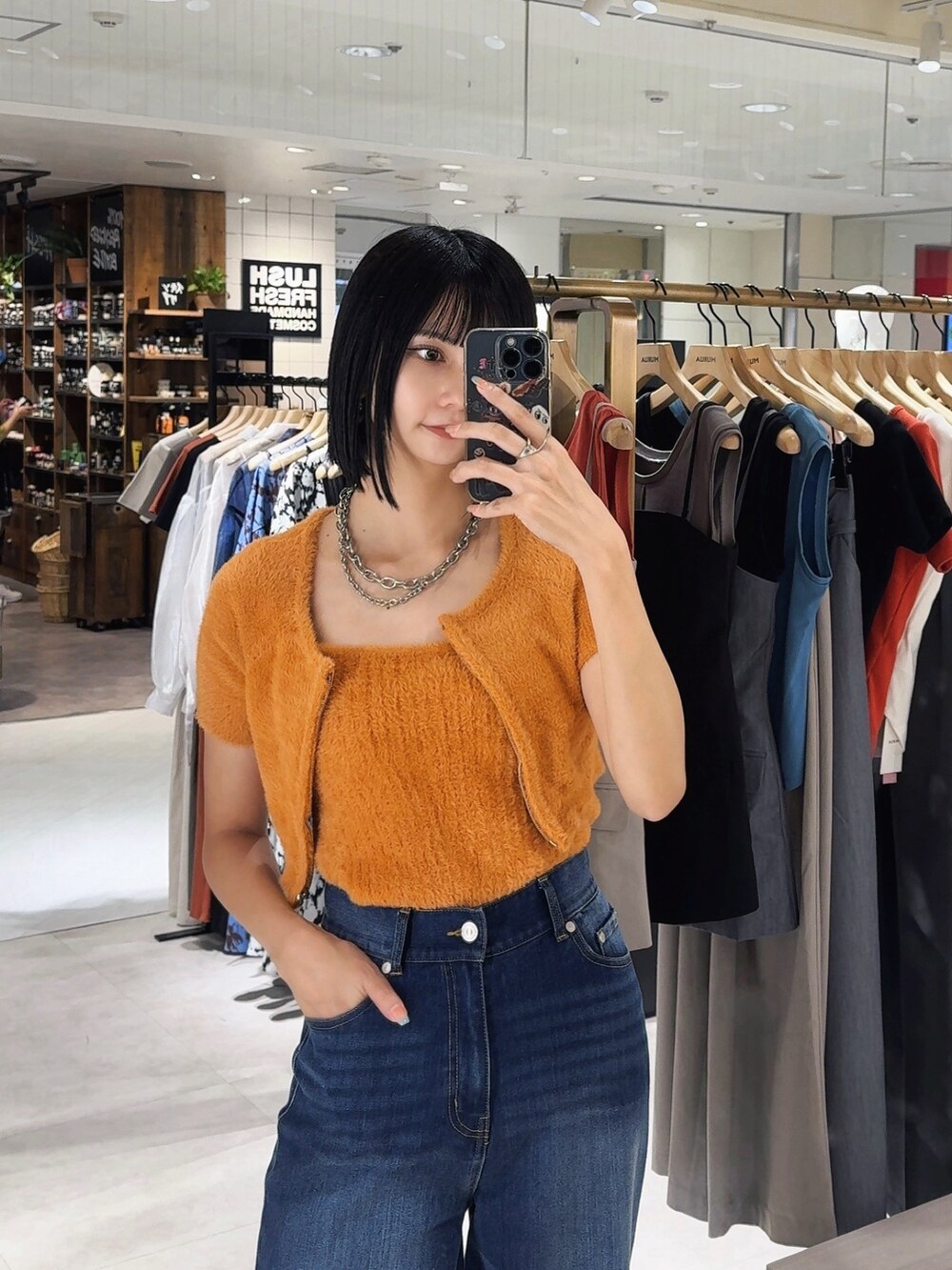 ブルー系のデニムパンツ、オレンジ系のニット/セーターを着用したレディースの秋コーディネートの2枚目の写真