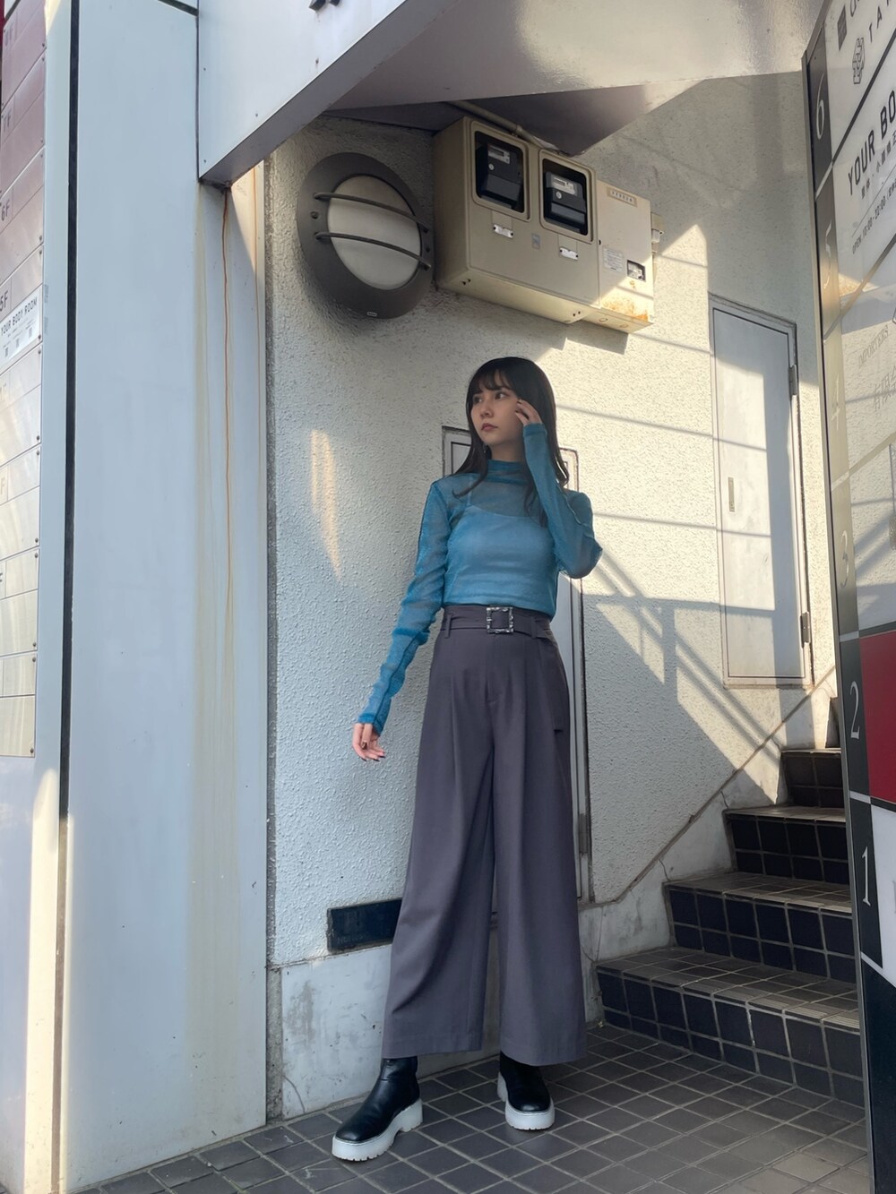 グレー系のスラックス、ブルー系のTシャツ/カットソー、ブラック系のブーツを着用したレディースの夏コーディネートの2枚目の写真