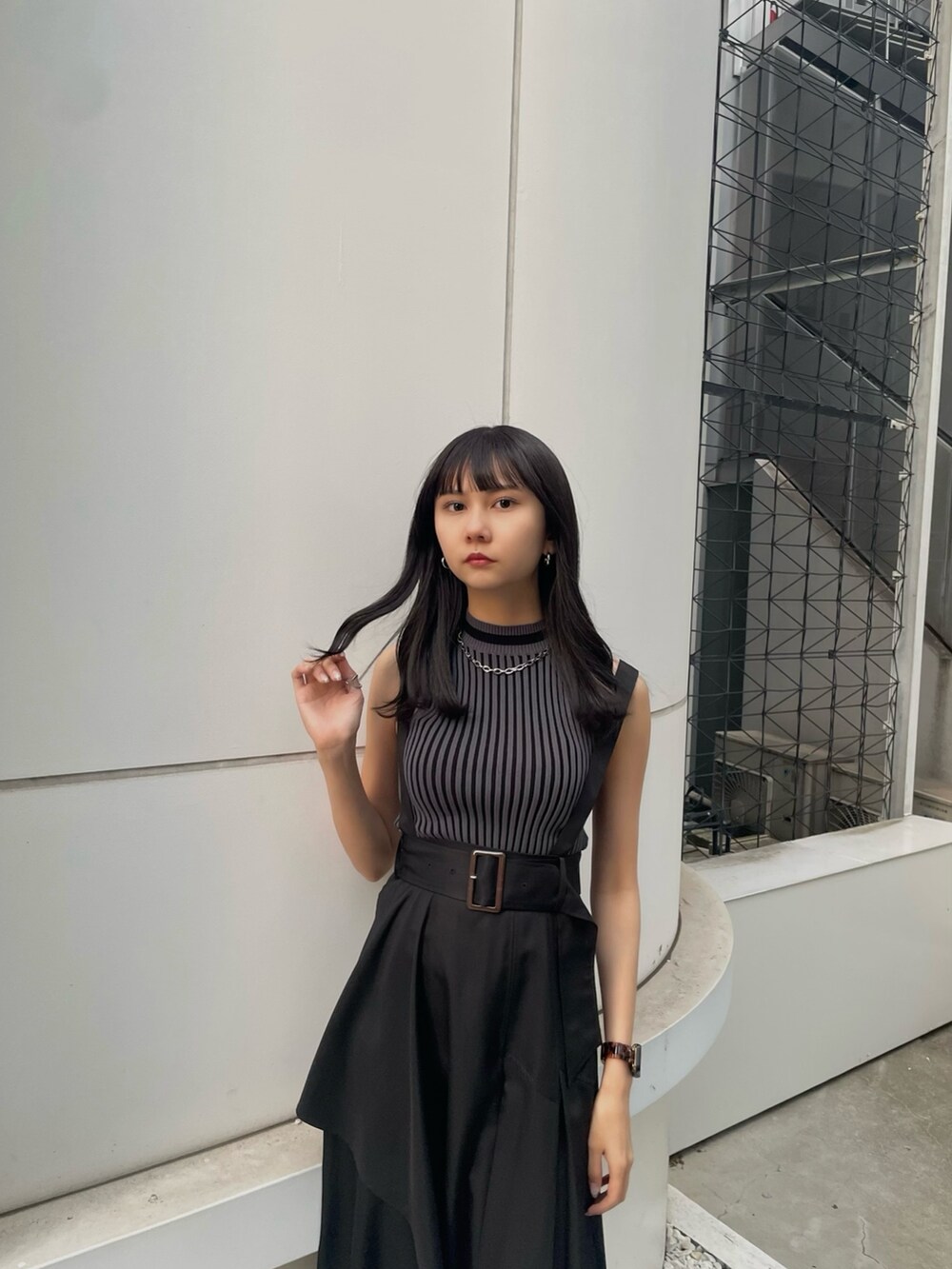 ブラック系のニット/セーター、ブラック系のジャンパースカート、ブラック系のサンダルを着用したレディースの春コーディネートの4枚目の写真