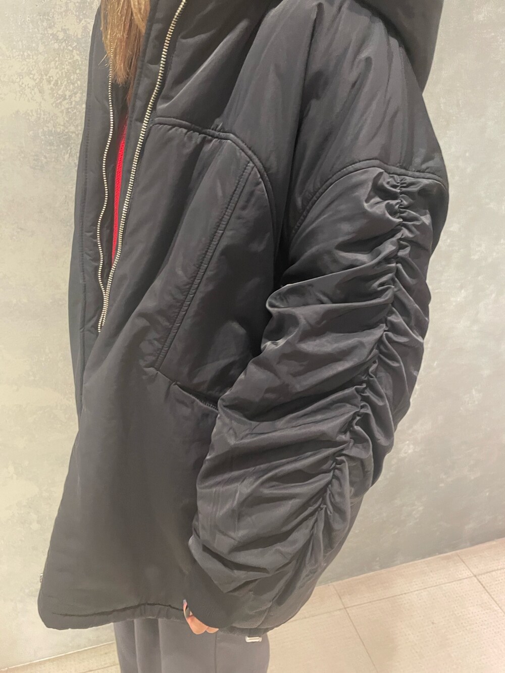 レッド系のニット/セーター、ブラック系のブルゾン、グレー系のスラックスを着用したレディースの冬コーディネートの7枚目の写真