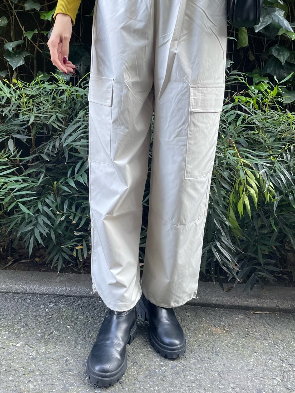 グリーン系のステンカラーコート、ホワイト系のカーゴパンツ、グリーン系のハンドバッグを着用したレディースの秋コーディネートの7枚目の写真