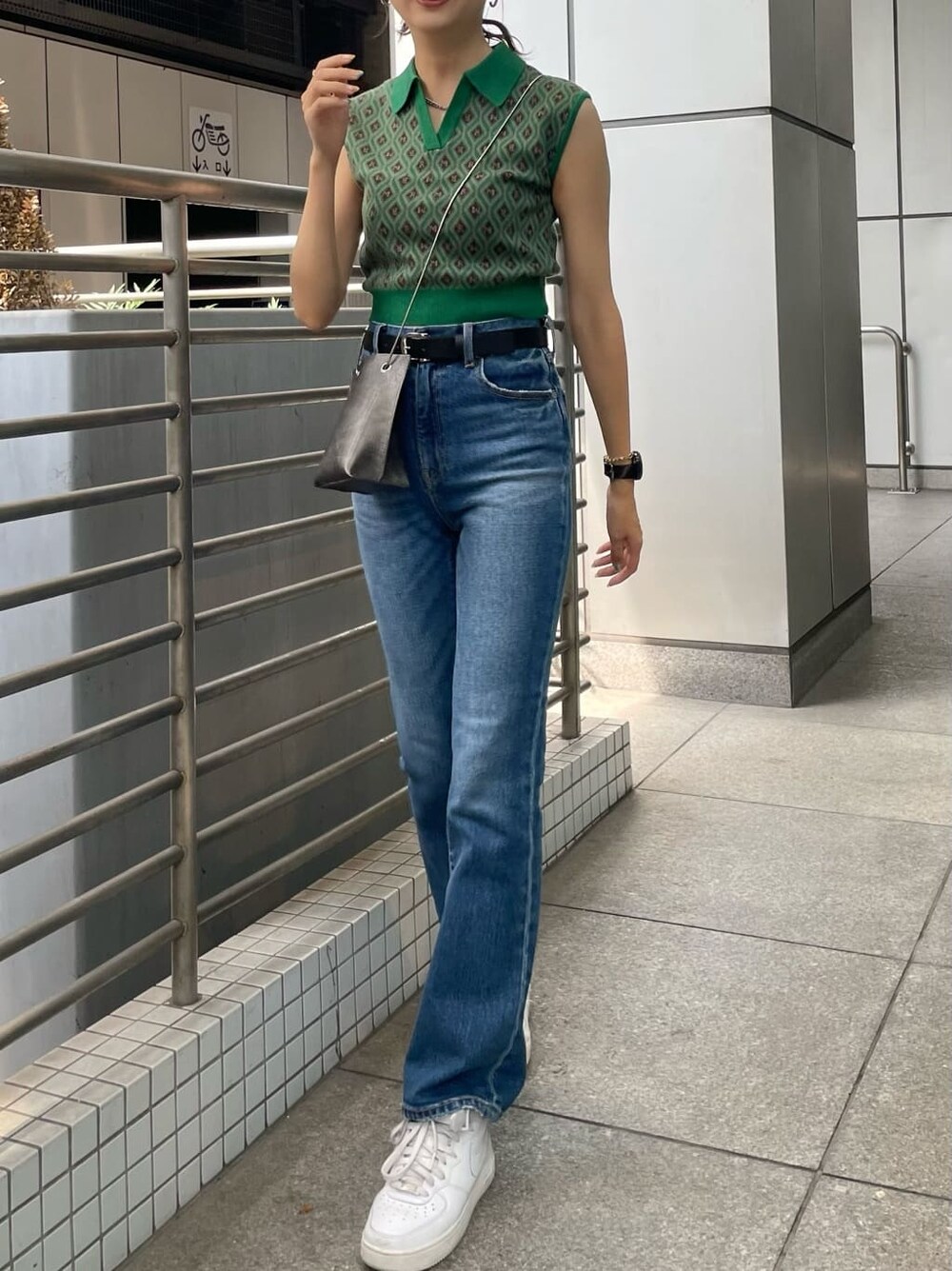 ブルー系のデニムパンツ、ブラック系のショルダーバッグ、グリーン系のニット/セーターを着用したレディースの夏コーディネートの2枚目の写真