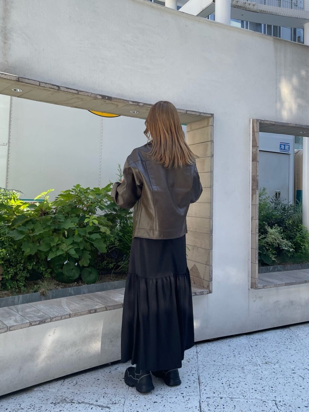 ブラック系のスカート、オレンジ系のニット/セーター、ブラック系のブーツを着用したレディースの秋コーディネートの3枚目の写真