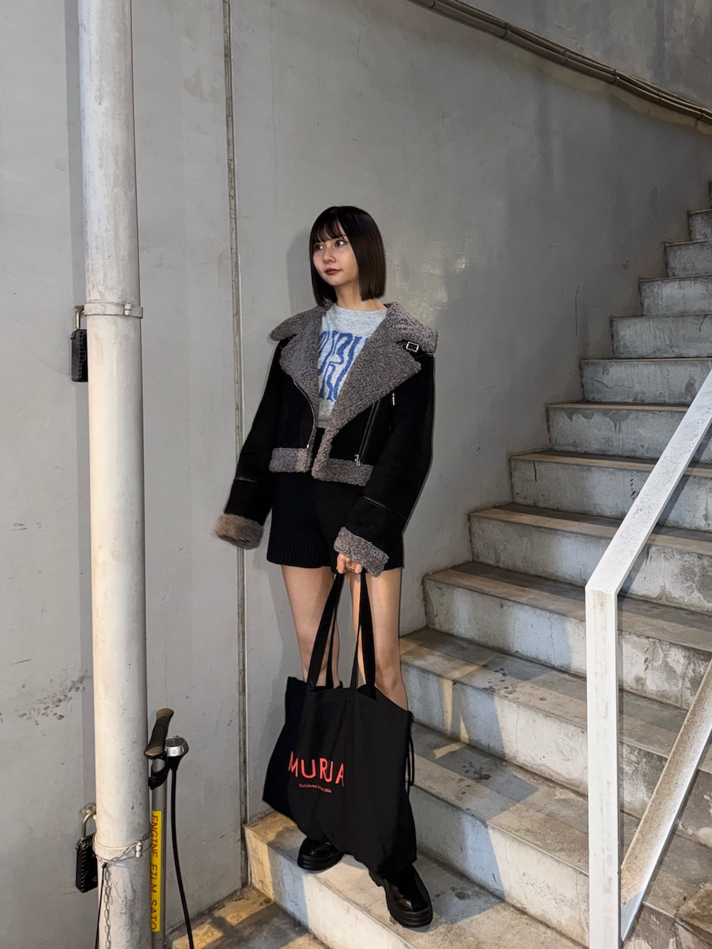 ブラック系のハンドバッグ、グレー系のニット/セーター、ブラック系のムートンコートを着用したレディースの冬コーディネートの3枚目の写真