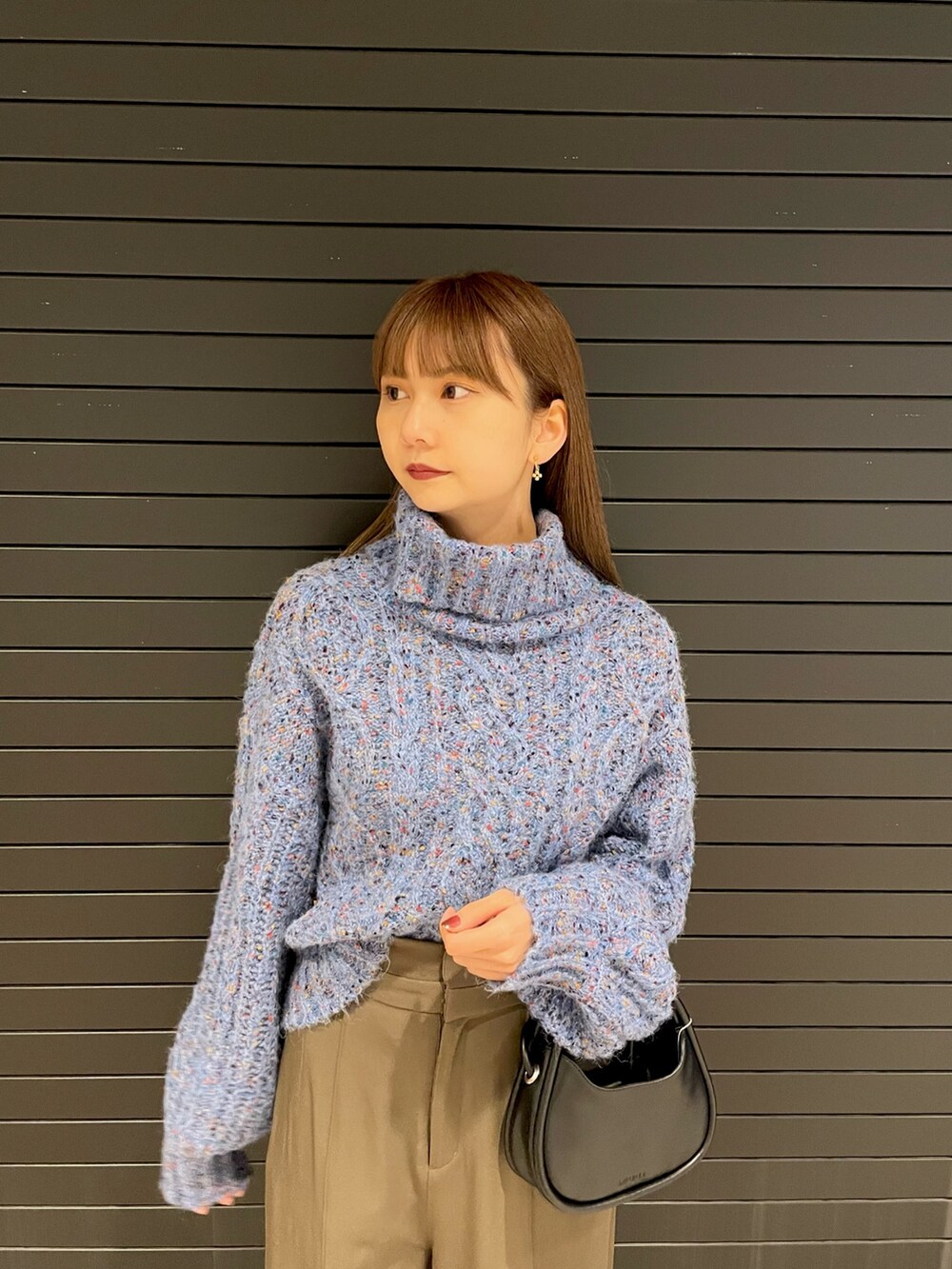 ブルー系のニット/セーター、ブラック系のハンドバッグ、ブラック系のブーツを着用したレディースの冬コーディネートの4枚目の写真