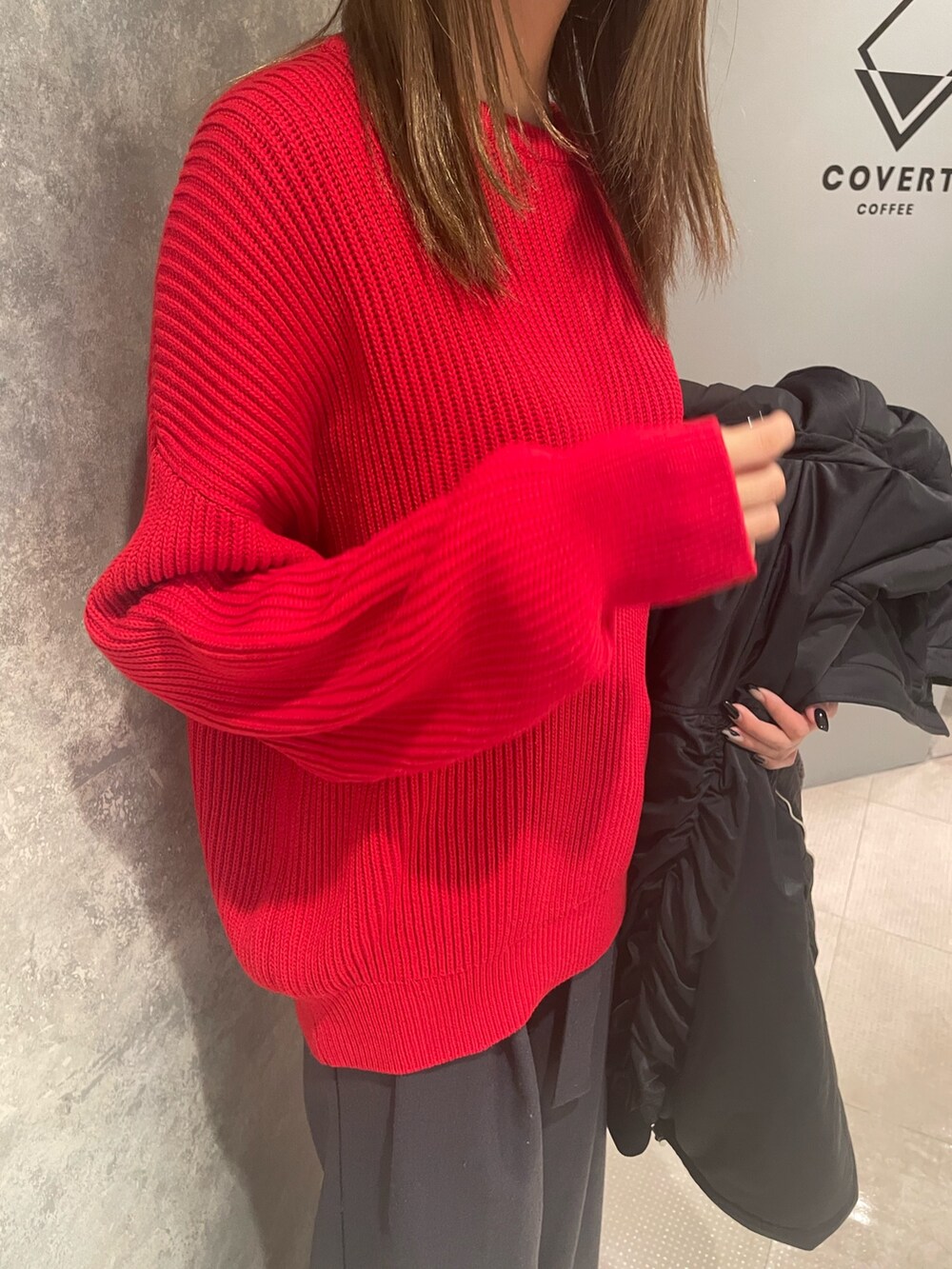 レッド系のニット/セーター、ブラック系のブルゾン、グレー系のスラックスを着用したレディースの冬コーディネートの6枚目の写真