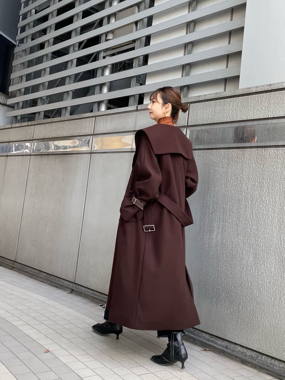 ブラック系のブーツ、ブラウン系のチェスターコート、ブラック系のデニムパンツを着用したレディースの冬コーディネートの3枚目の写真