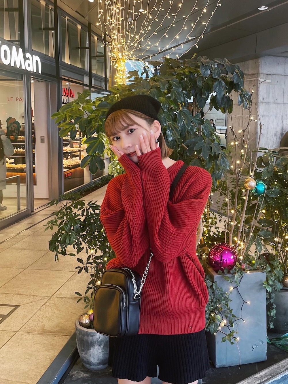 レッド系のニット/セーター、ブラック系のブーツ、ブラック系のニットキャップ/ビーニーを着用したレディースの冬コーディネートの3枚目の写真