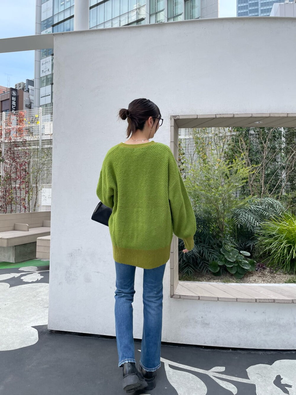 ブラック系のブーツ、ブルー系のデニムパンツ、ブラック系のハンドバッグを着用したレディースの春コーディネートの3枚目の写真
