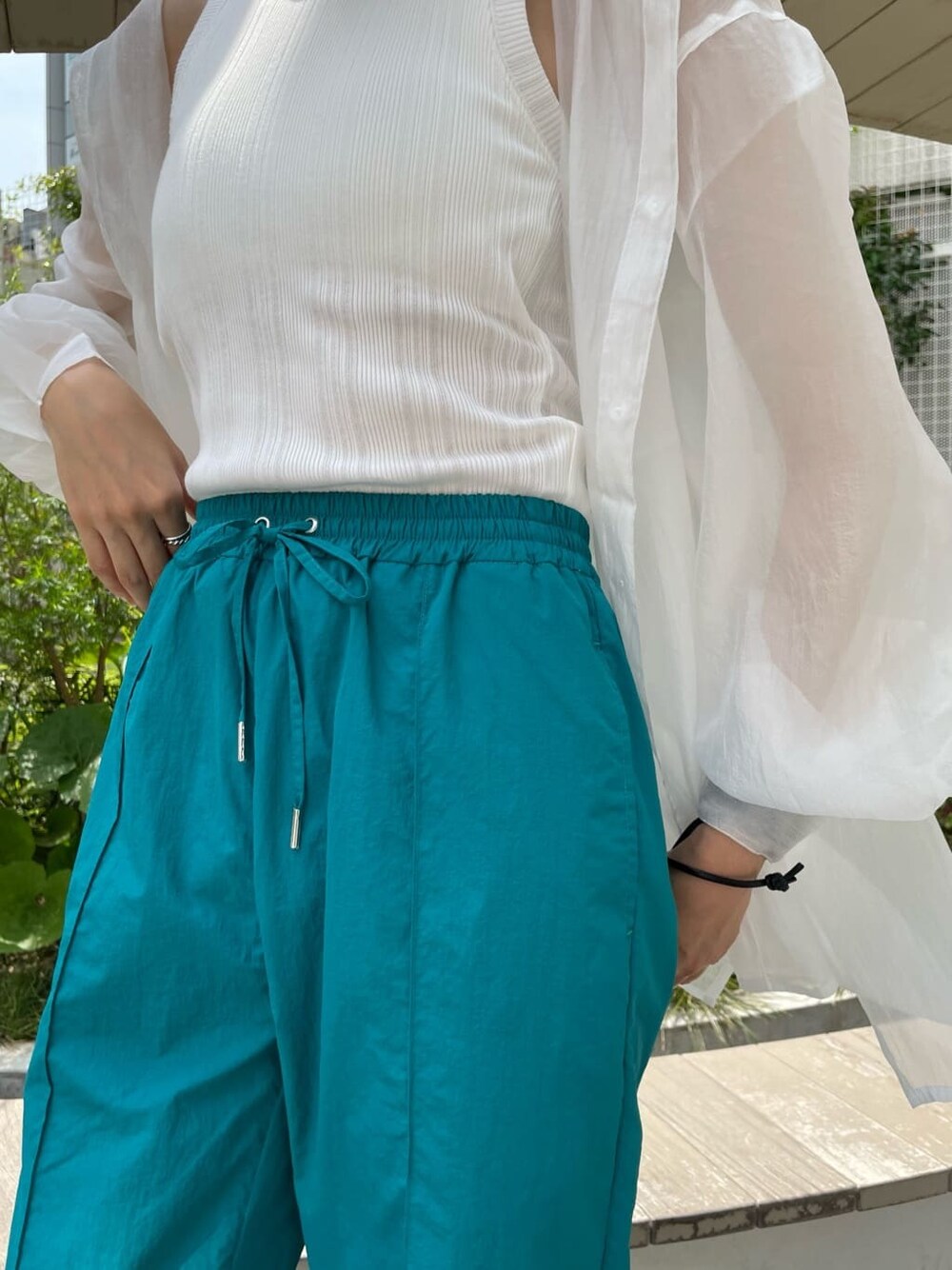 ブラック系のハンドバッグ、ホワイト系のシャツ/ブラウス、ブラック系のサンダルを着用したレディースの夏コーディネートの5枚目の写真