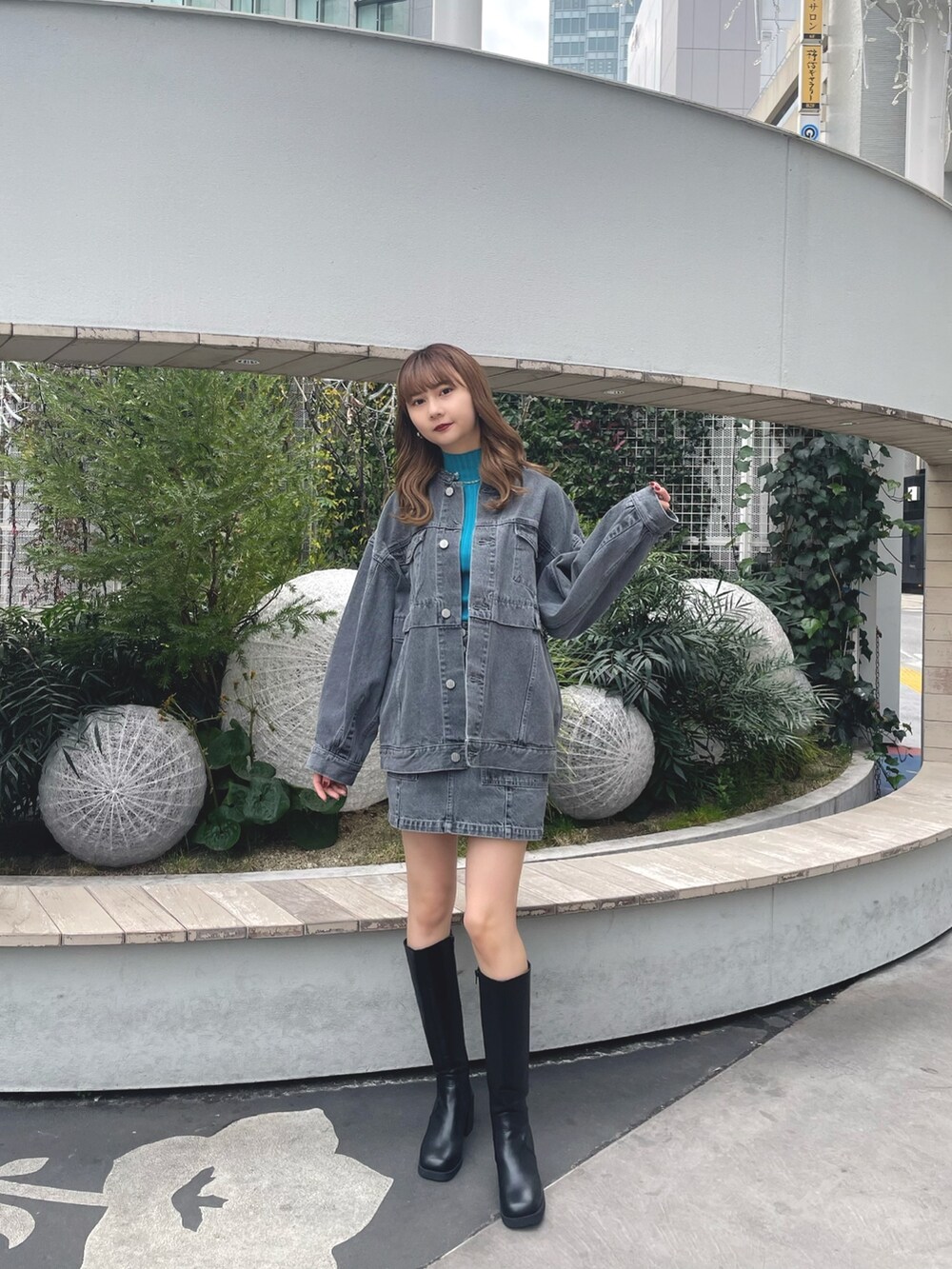 グレー系のデニムジャケット、グレー系のスカート、ブラック系のブーツを着用したレディースの冬コーディネートの2枚目の写真