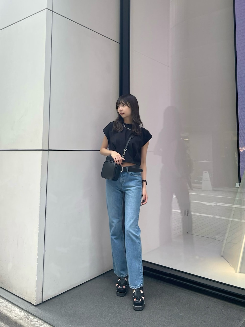 ブラック系のTシャツ/カットソー、ブルー系のデニムパンツ、ブラック系のサンダルを着用したレディースの春コーディネートの2枚目の写真