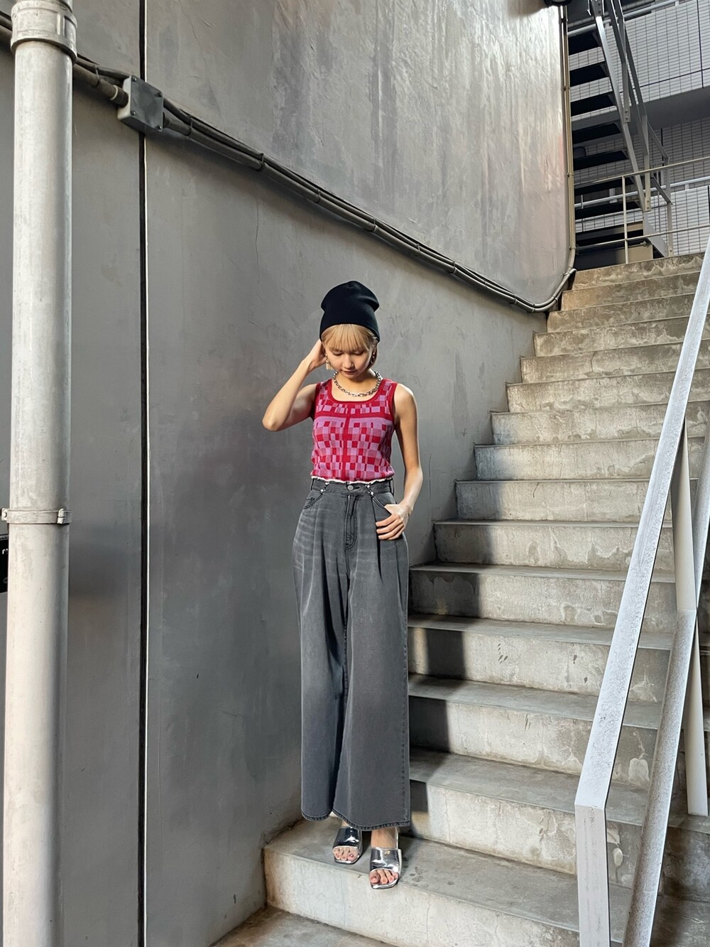 レッド系のタンクトップ、ブラック系のデニムパンツ、シルバー系のサンダルを着用したレディースの冬コーディネートの3枚目の写真