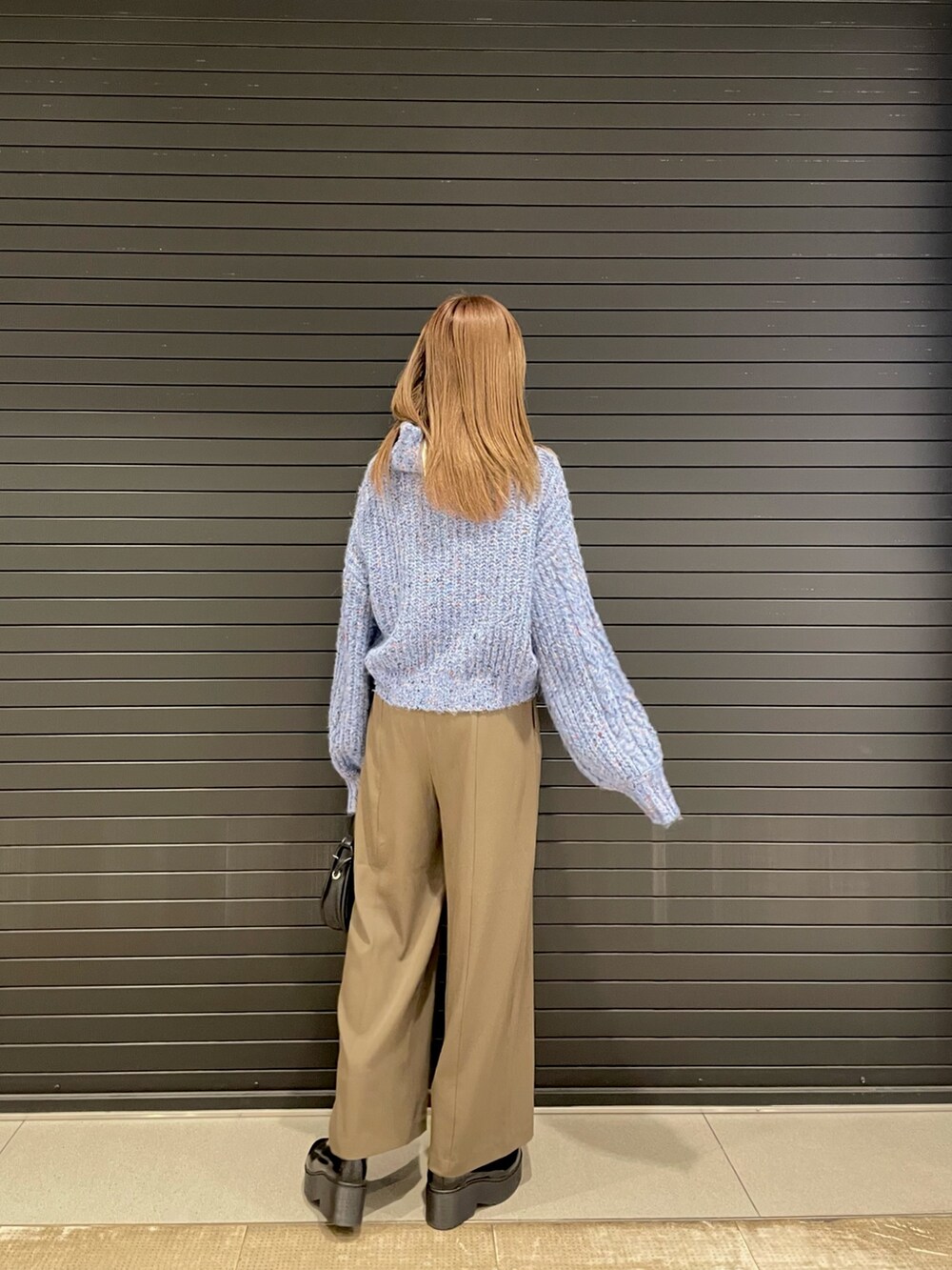 ブルー系のニット/セーター、ブラック系のハンドバッグ、ブラック系のブーツを着用したレディースの冬コーディネートの3枚目の写真