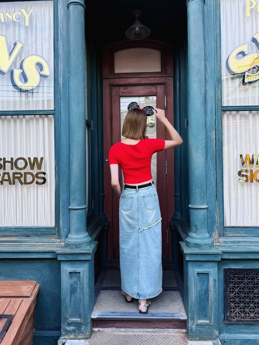 ブルー系のデニムスカート、レッド系のニット/セーター、シルバー系のパンプスを着用したレディースの夏コーディネートの3枚目の写真