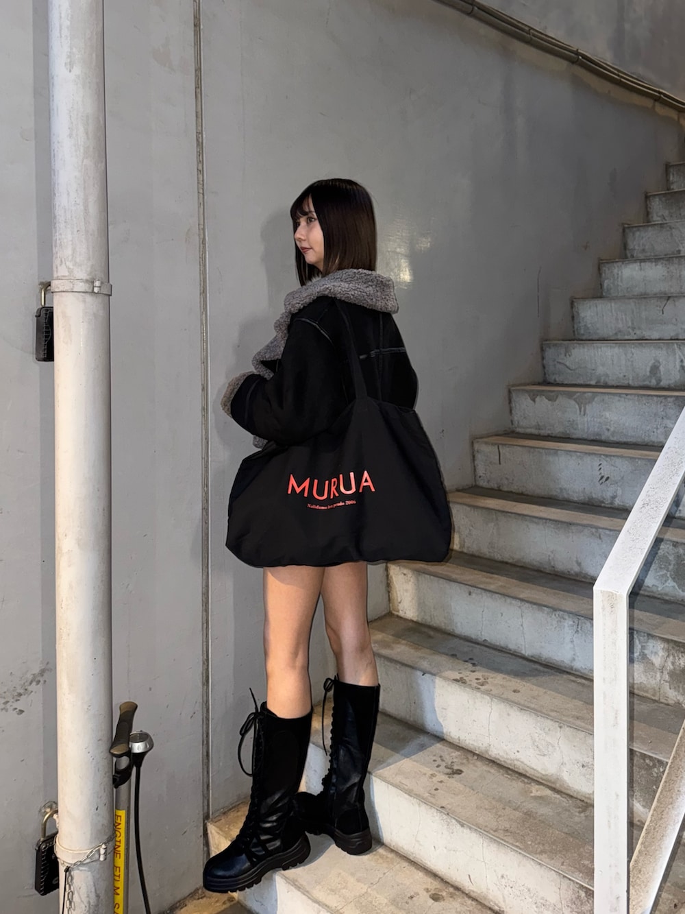 ブラック系のハンドバッグ、グレー系のニット/セーター、ブラック系のムートンコートを着用したレディースの冬コーディネートの4枚目の写真