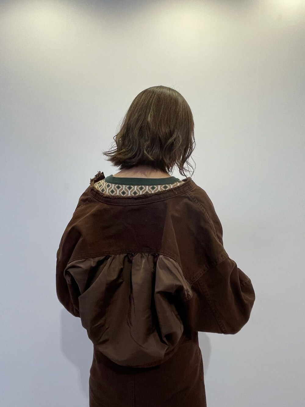 ブラウン系のブルゾン、ブラウン系のスカート、ホワイト系のブーツを着用したレディースの秋コーディネートの4枚目の写真