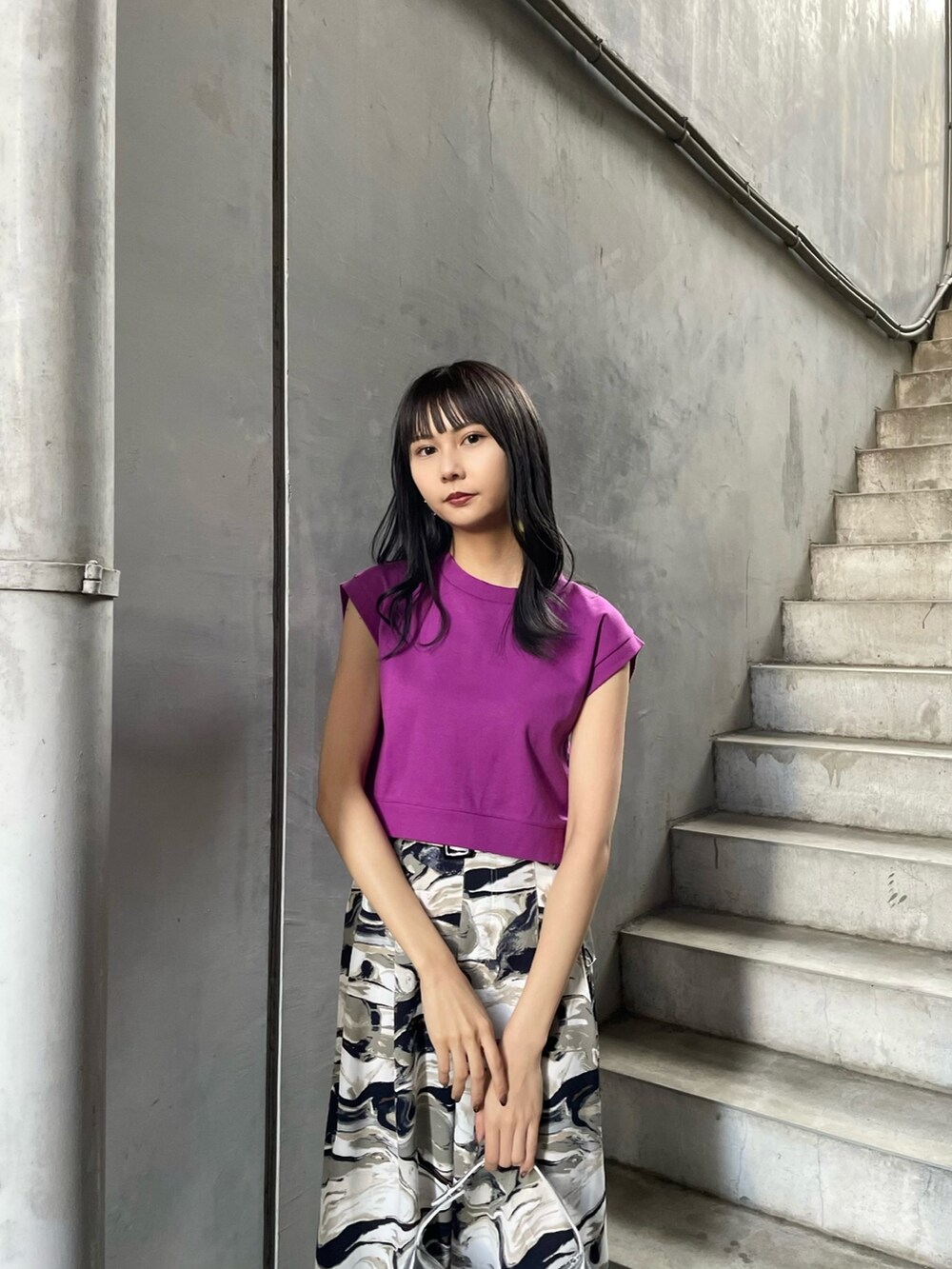 パープル系のタンクトップ、シルバー系のハンドバッグ、ブルー系のスラックスを着用したレディースの春コーディネートの4枚目の写真