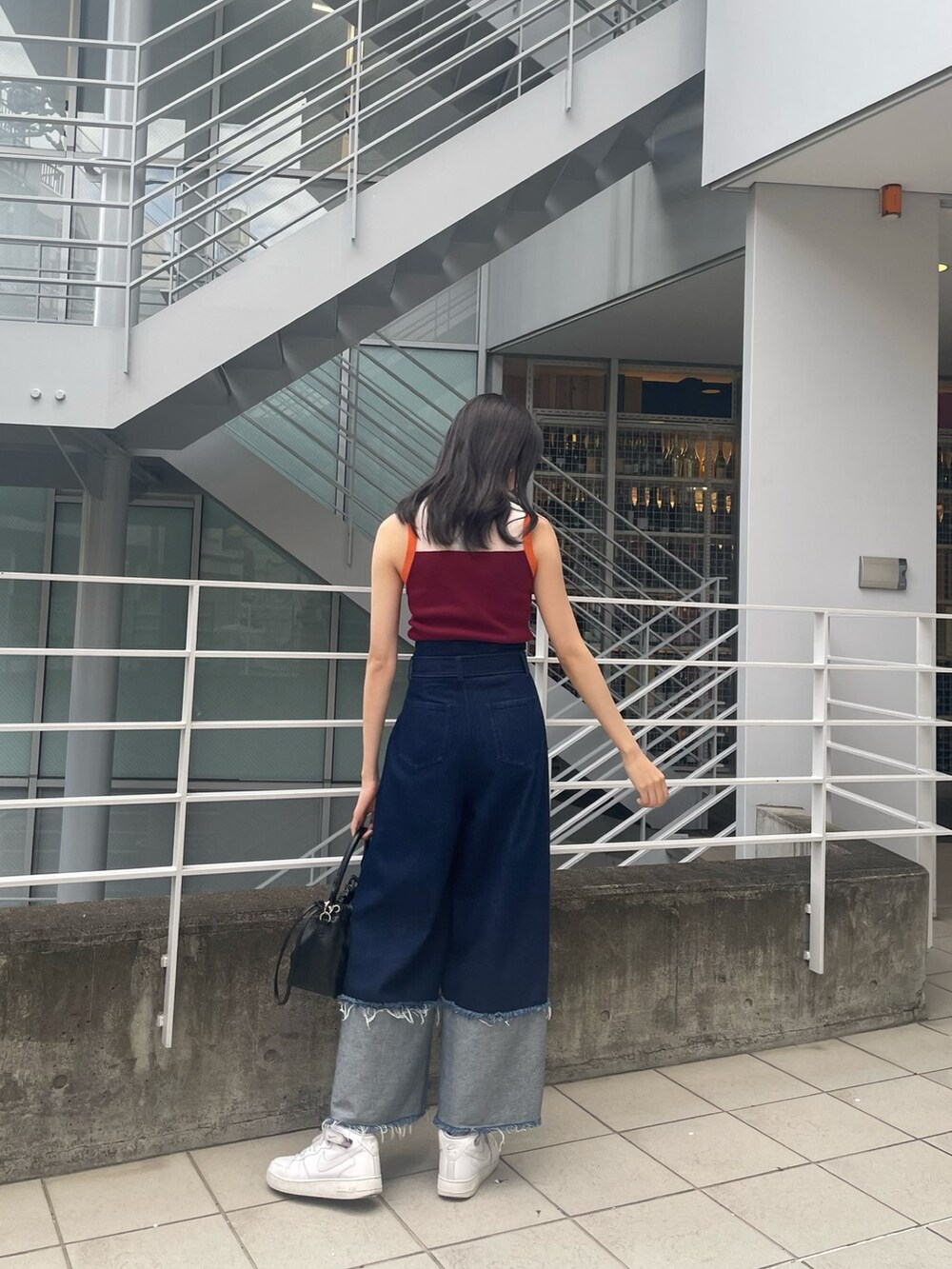 ブルー系のニット/セーター、ブラック系のハンドバッグ、ブルー系のデニムパンツを着用したレディースの春コーディネートの3枚目の写真