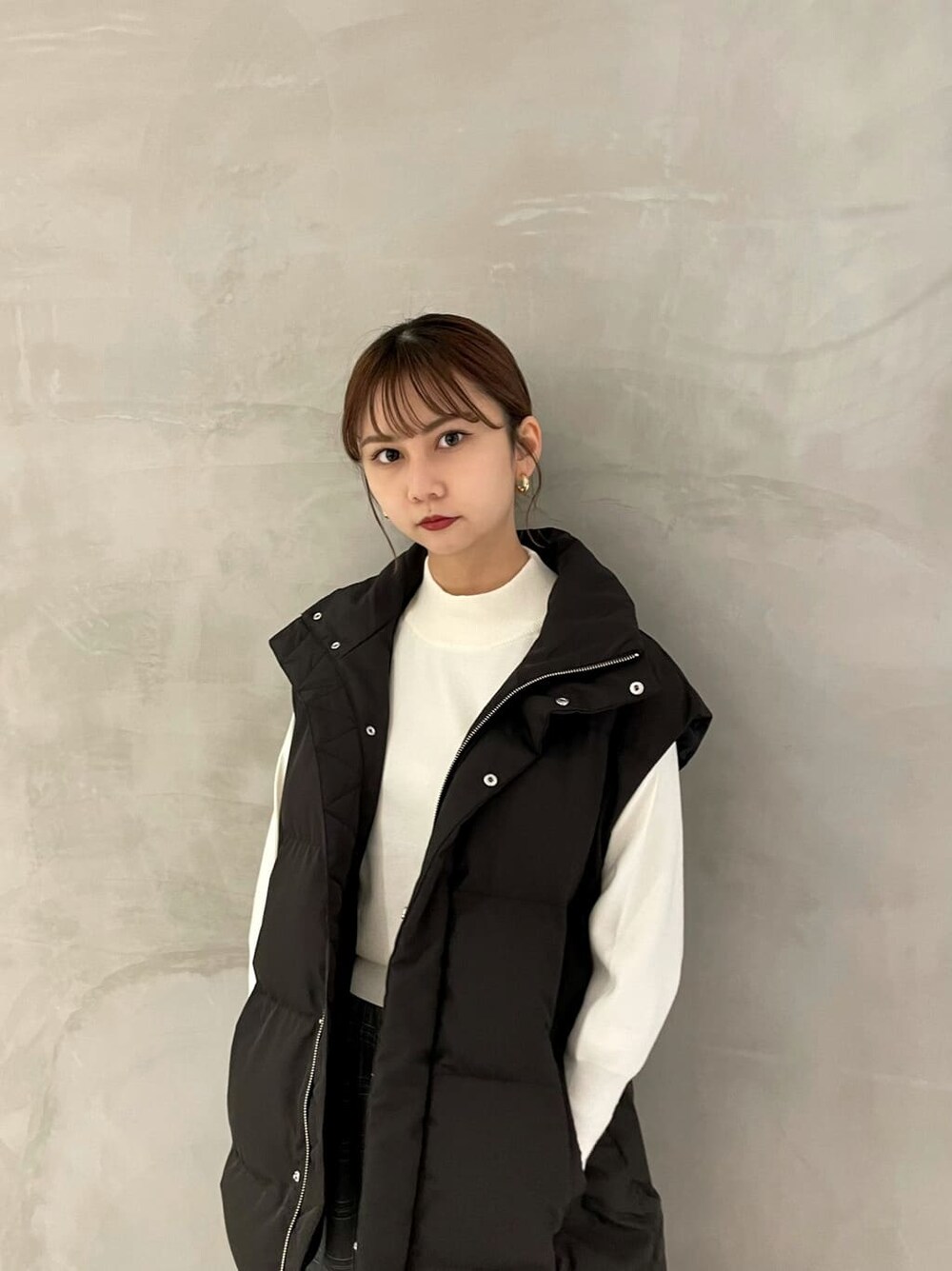 ブラック系のダウンベスト、その他のスカート、ブラウン系のブーツを着用したレディースの秋コーディネートの3枚目の写真