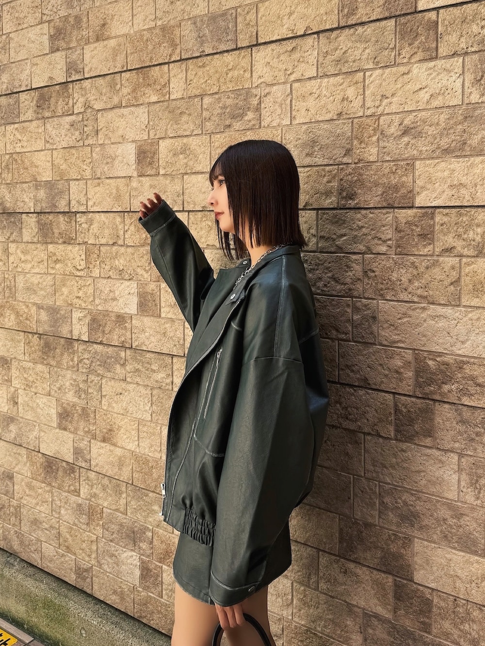 ブルー系のライダースジャケット、ブルー系のスカート、ブラック系のブーツを着用したレディースの秋コーディネートの4枚目の写真