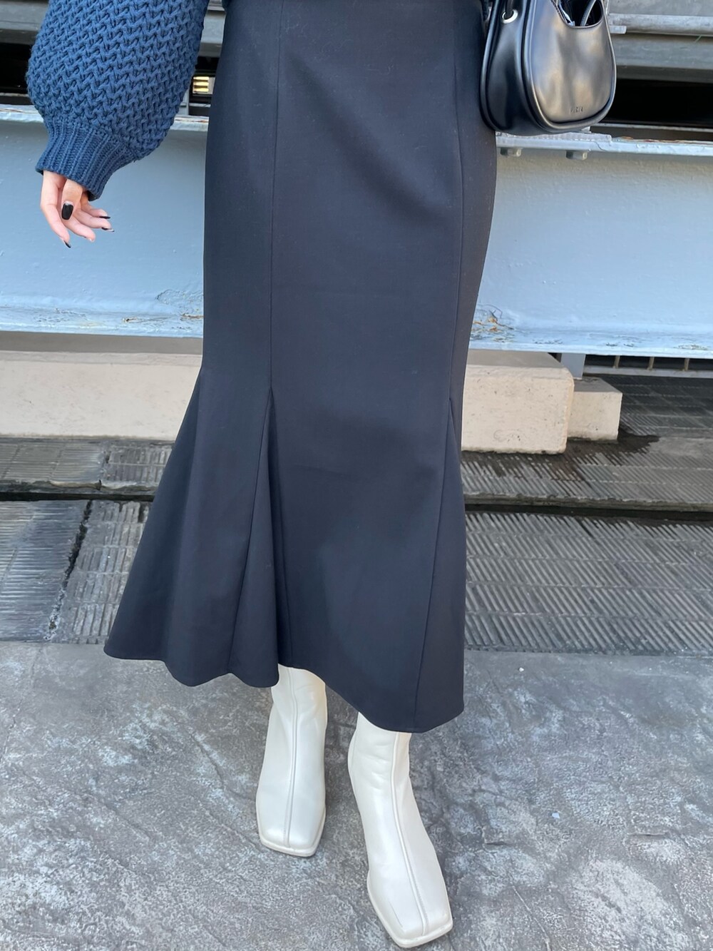 ブルー系のニット/セーター、ブラック系のハンドバッグ、ブラック系のスカートを着用したレディースの冬コーディネートの7枚目の写真