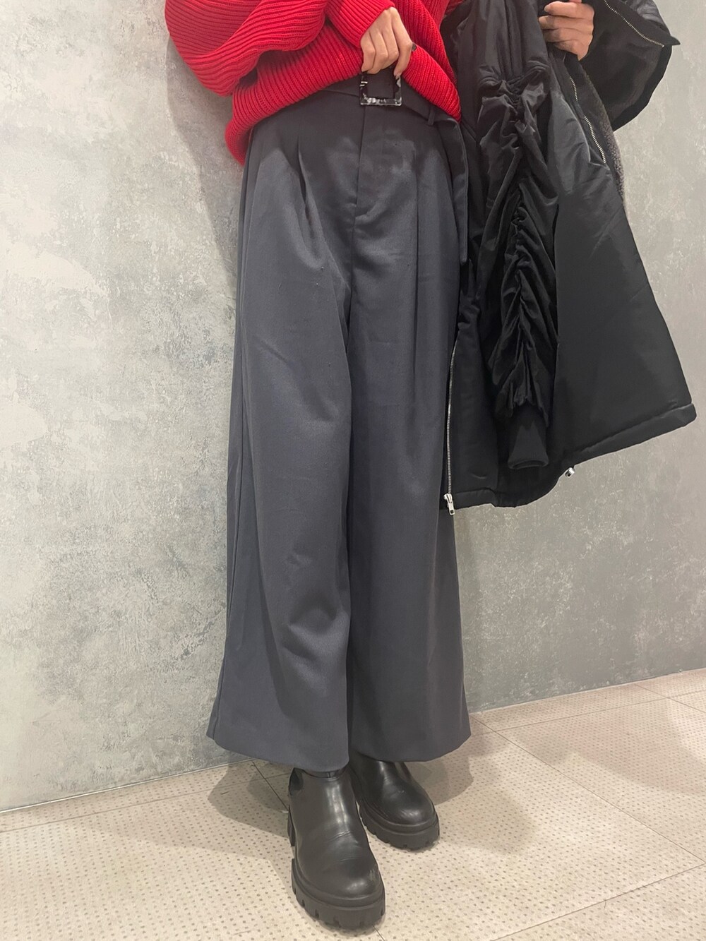 レッド系のニット/セーター、ブラック系のブルゾン、グレー系のスラックスを着用したレディースの冬コーディネートの8枚目の写真