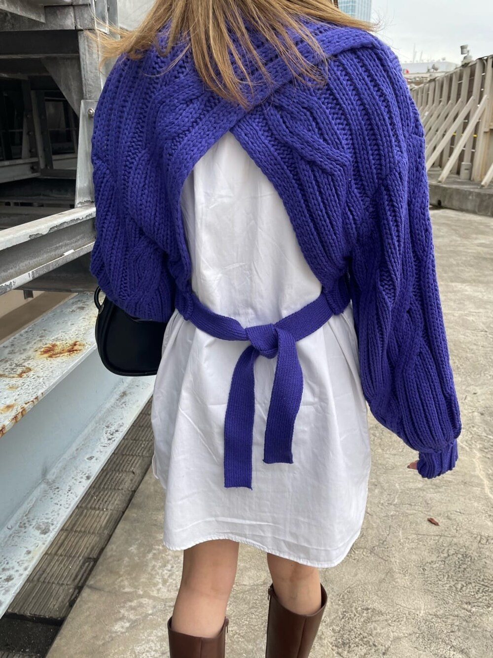 ブラウン系のムートンコート、ブラック系のハンドバッグ、ブラウン系のブーツを着用したレディースの秋コーディネートの9枚目の写真