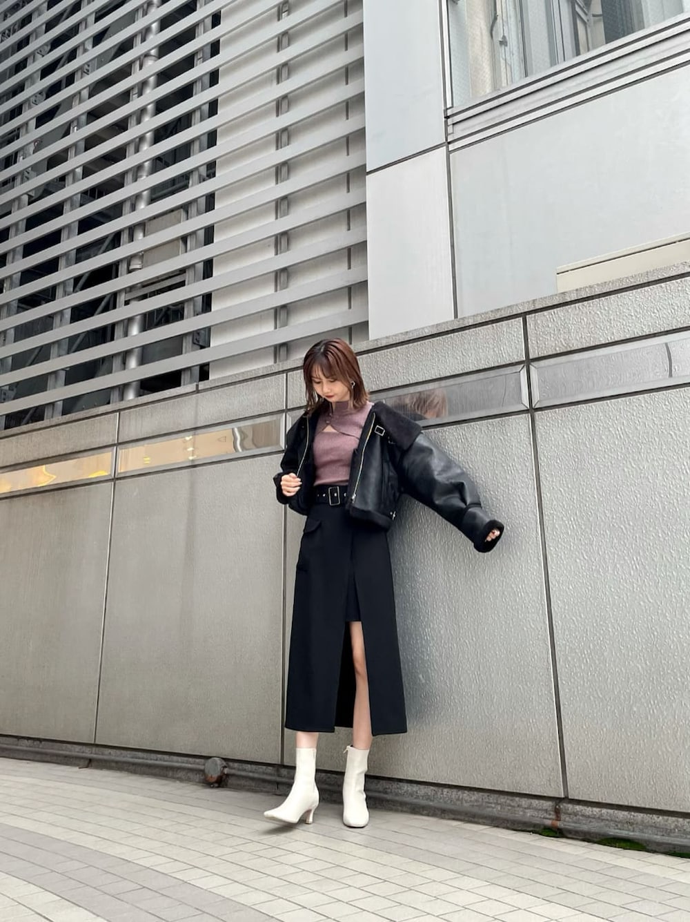 ブラック系のスカート、ブラック系のブルゾン、ホワイト系のブーツを着用したレディースの秋コーディネートの2枚目の写真