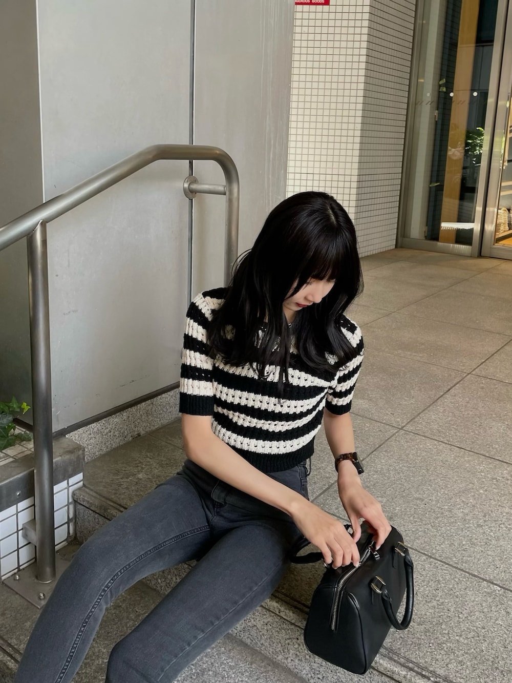 ブラック系のニット/セーター、グレー系のデニムパンツ、ブラック系のサンダルを着用したレディースの春コーディネートの2枚目の写真