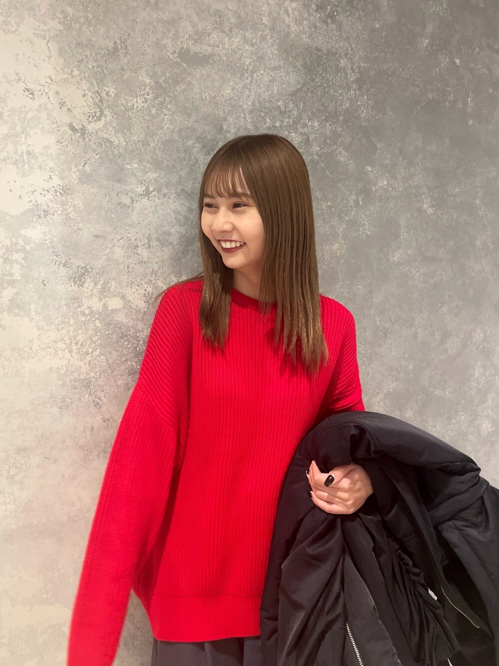 レッド系のニット/セーター、ブラック系のブルゾン、グレー系のスラックスを着用したレディースの冬コーディネートの5枚目の写真