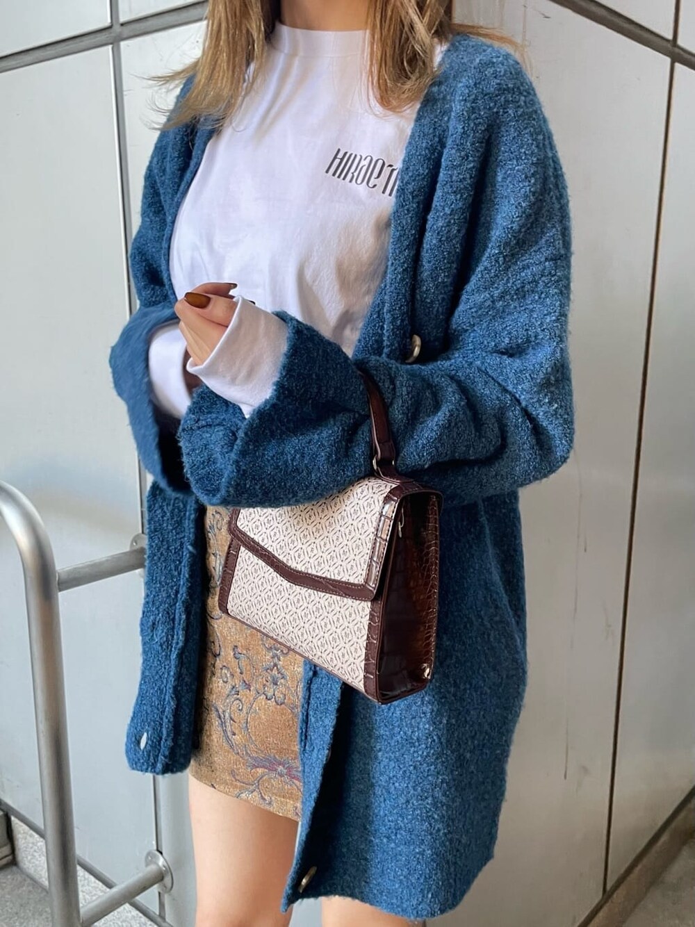 ホワイト系のTシャツ/カットソー、ブラウン系のスカート、ブルー系のカーディガン/ボレロを着用したレディースの秋コーディネートの6枚目の写真