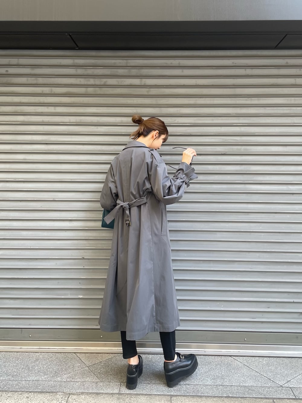 ブルー系のハンドバッグ、グレー系のトレンチコート、ブラック系のニット/セーターを着用したレディースの冬コーディネートの4枚目の写真