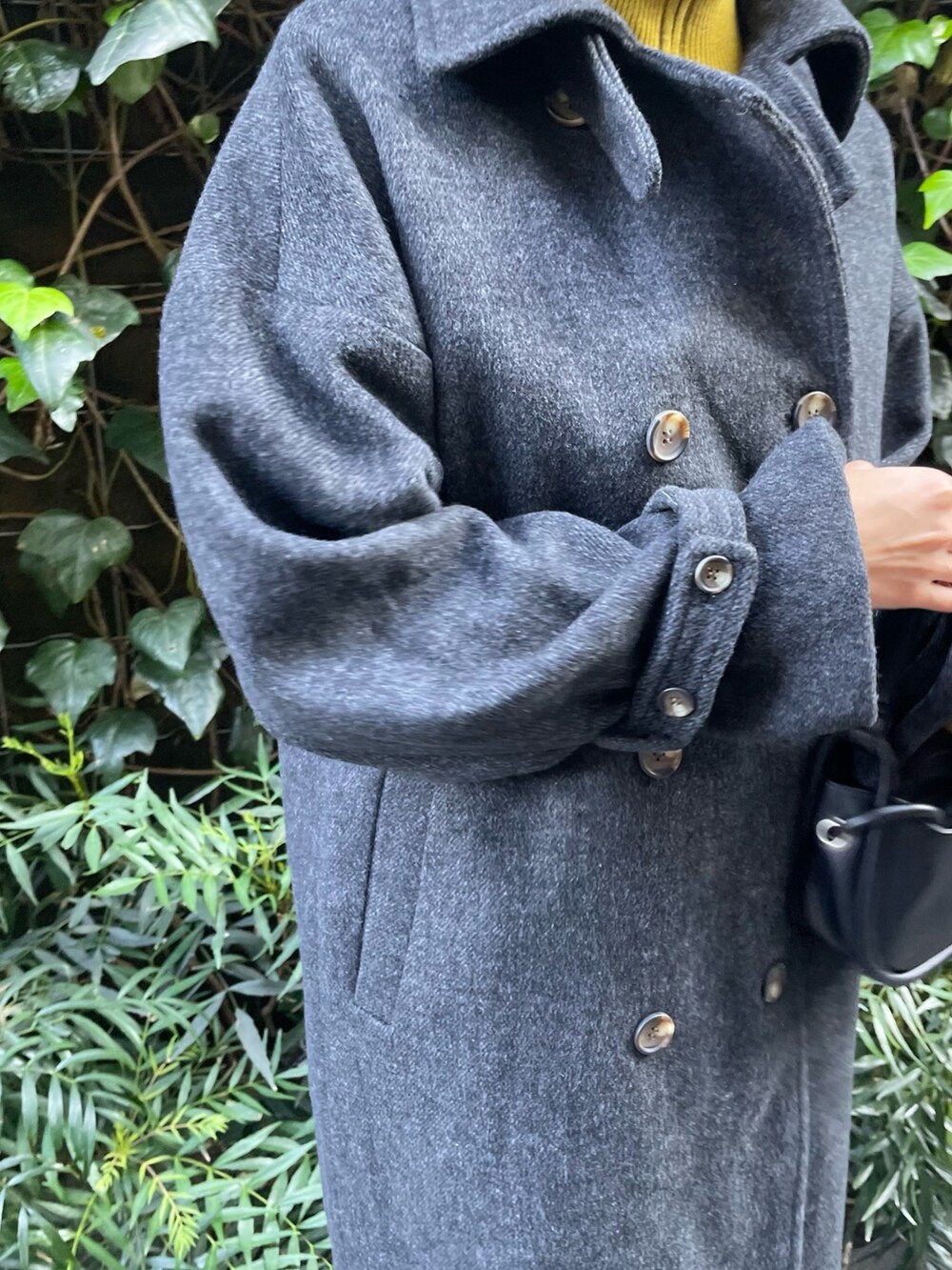 グリーン系のステンカラーコート、ホワイト系のカーゴパンツ、グリーン系のハンドバッグを着用したレディースの秋コーディネートの5枚目の写真