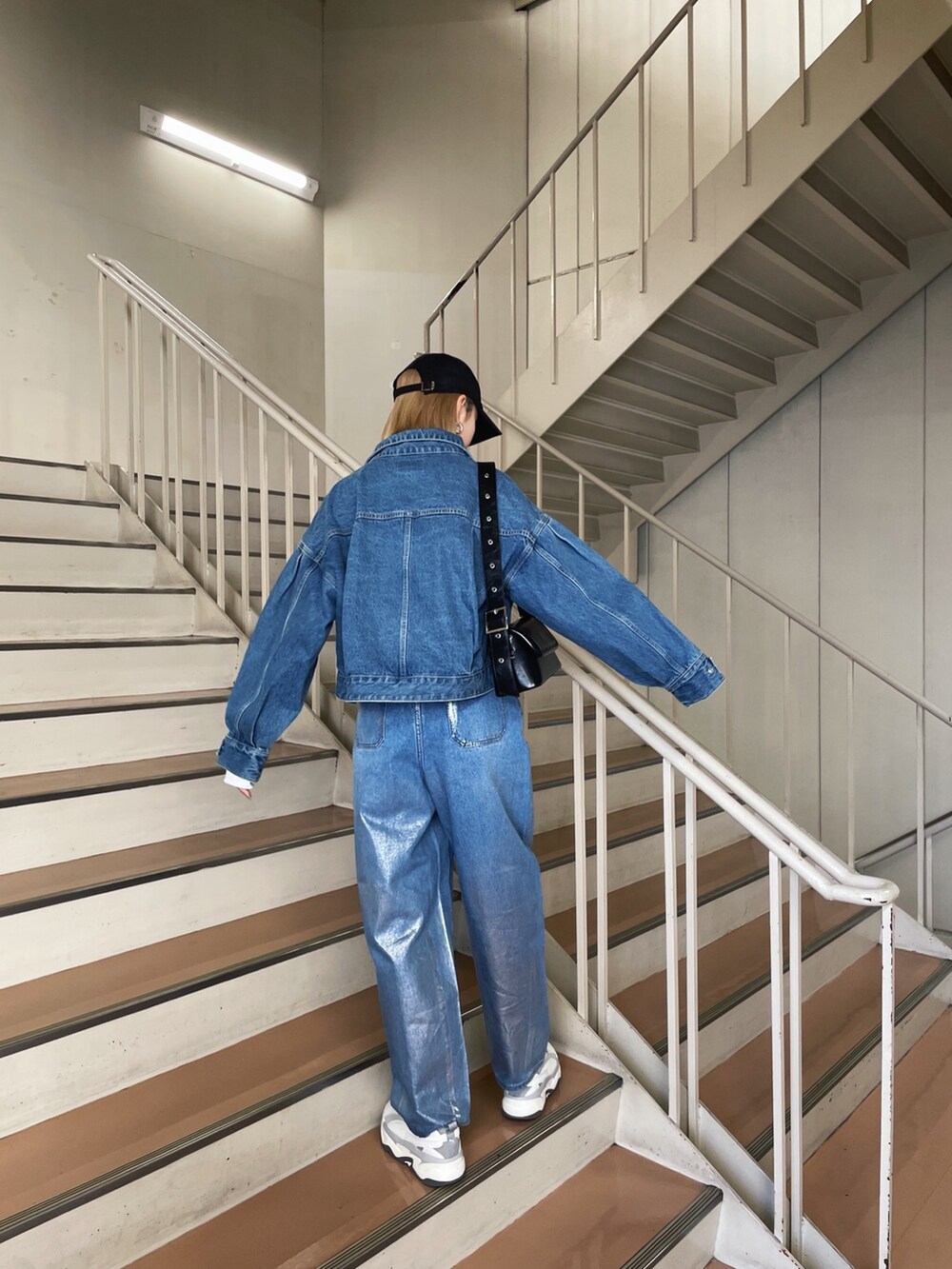 グレー系のスニーカー、ブルー系のデニムパンツ、ブルー系のデニムジャケットを着用したレディースの冬コーディネートの5枚目の写真