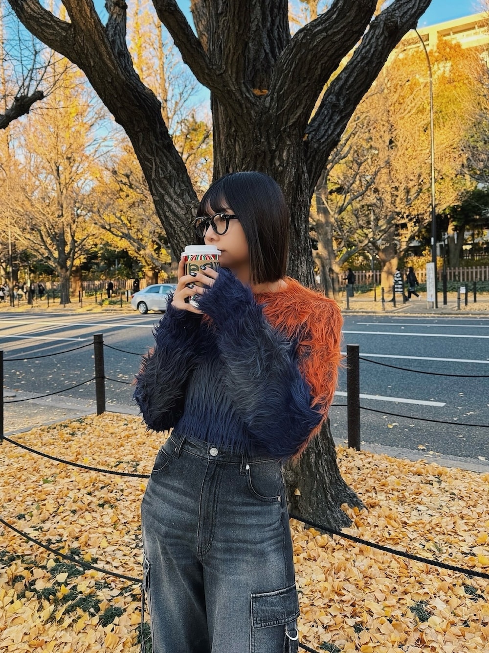 オレンジ系のニット/セーター、ブラック系のデニムパンツ、ブラック系のブーツを着用したレディースの冬コーディネートの2枚目の写真