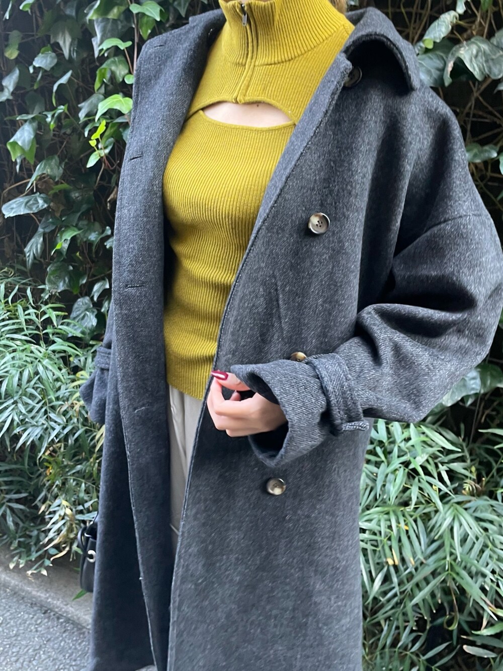 グリーン系のステンカラーコート、ホワイト系のカーゴパンツ、グリーン系のハンドバッグを着用したレディースの秋コーディネートの3枚目の写真