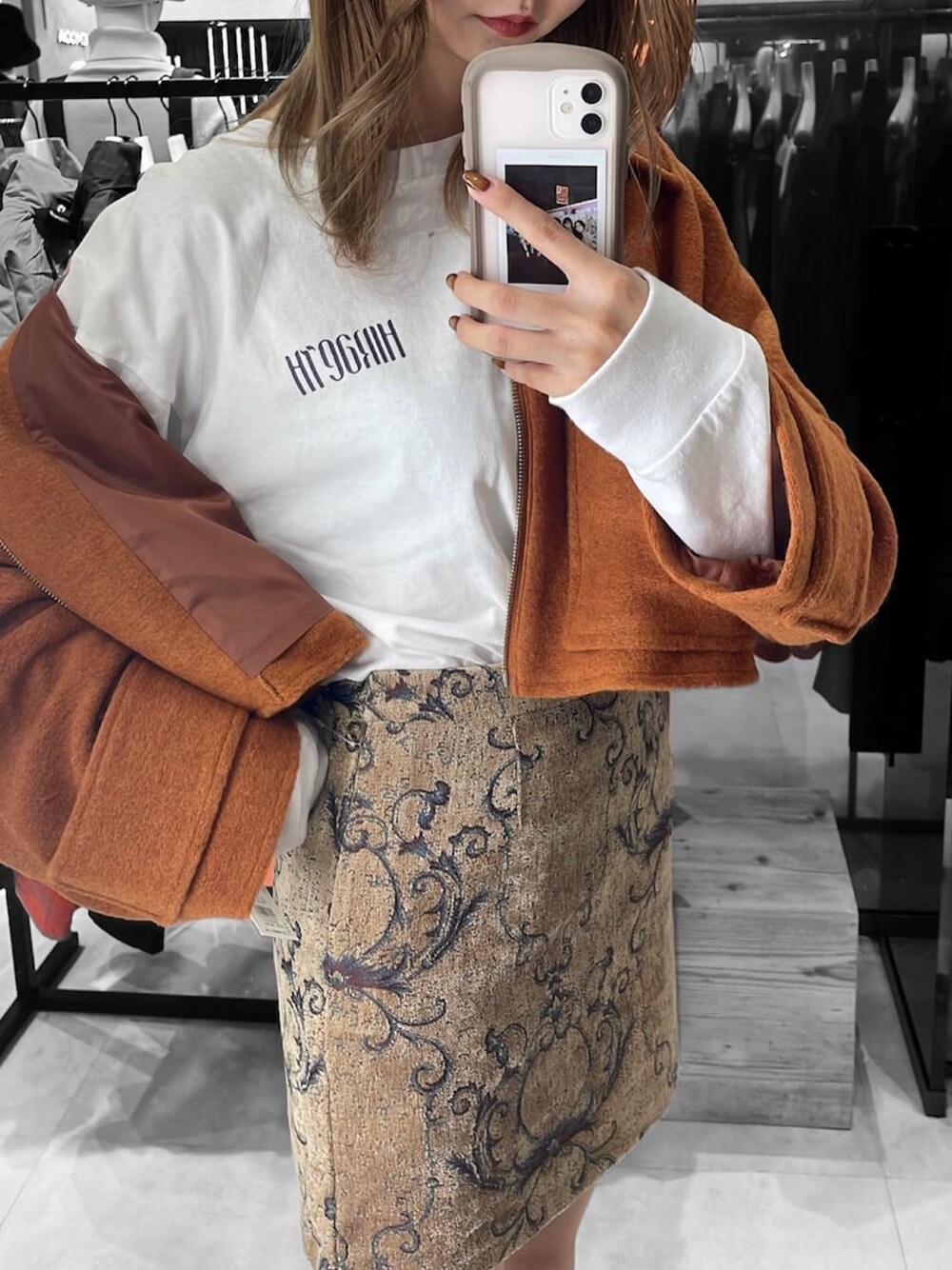 ホワイト系のTシャツ/カットソー、オレンジ系のブルゾン、ブラウン系のスカートを着用したレディースの秋コーディネートの4枚目の写真