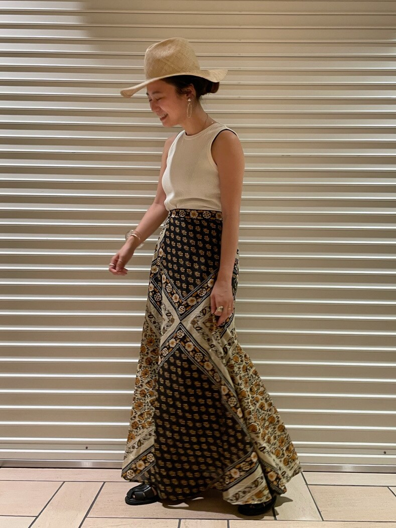 ホワイト系のタンクトップ、イエロー系のスカート、ベージュ系のハットを着用したレディースの夏コーディネートの2枚目の写真