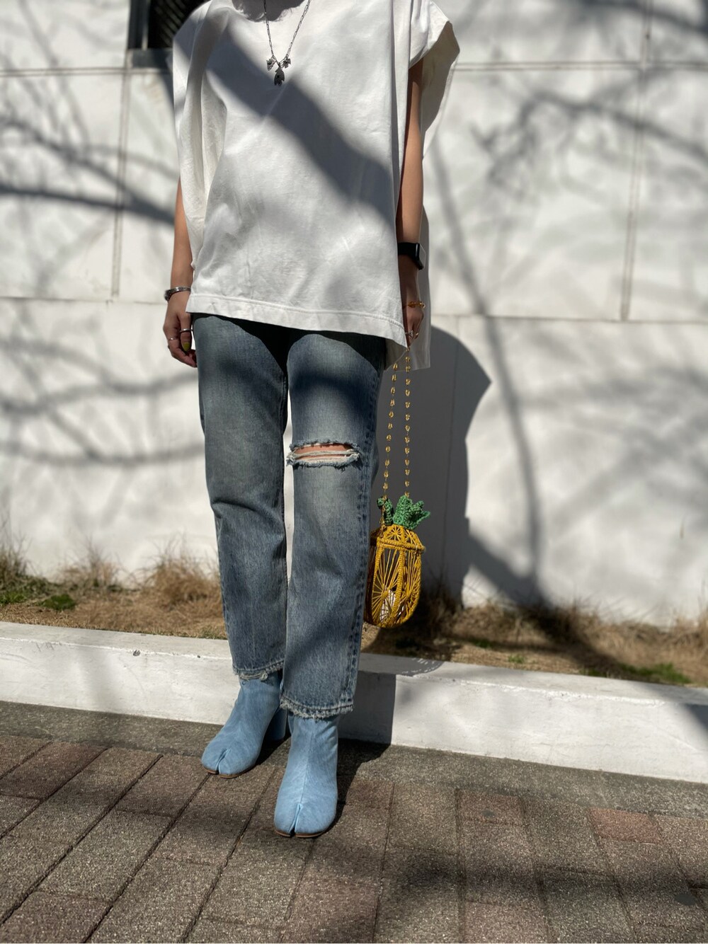 ブルー系のデニムパンツ、イエロー系のショルダーバッグ、ホワイト系のTシャツ/カットソーを着用したレディースの春コーディネートの3枚目の写真