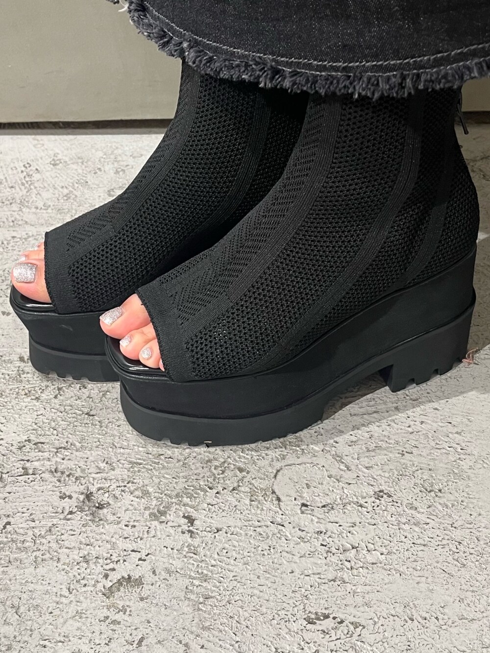 グレー系のニット/セーター、ブラック系のデニムスカート、ブラック系のブーツを着用したレディースの春コーディネートの6枚目の写真