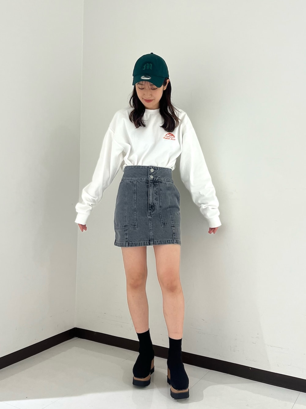 ホワイト系のTシャツ/カットソー、グレー系のスカート、ブラック系のブーツを着用したレディースの冬コーディネートの2枚目の写真